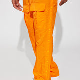 Pantalones de carga de nylon con broches en color naranja.