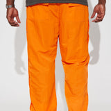 Pantalones de carga de nylon con broches en color naranja.
