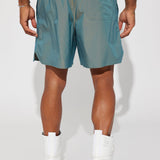 Shorts de nylon iridiscente con estampado de tormenta y color verde.